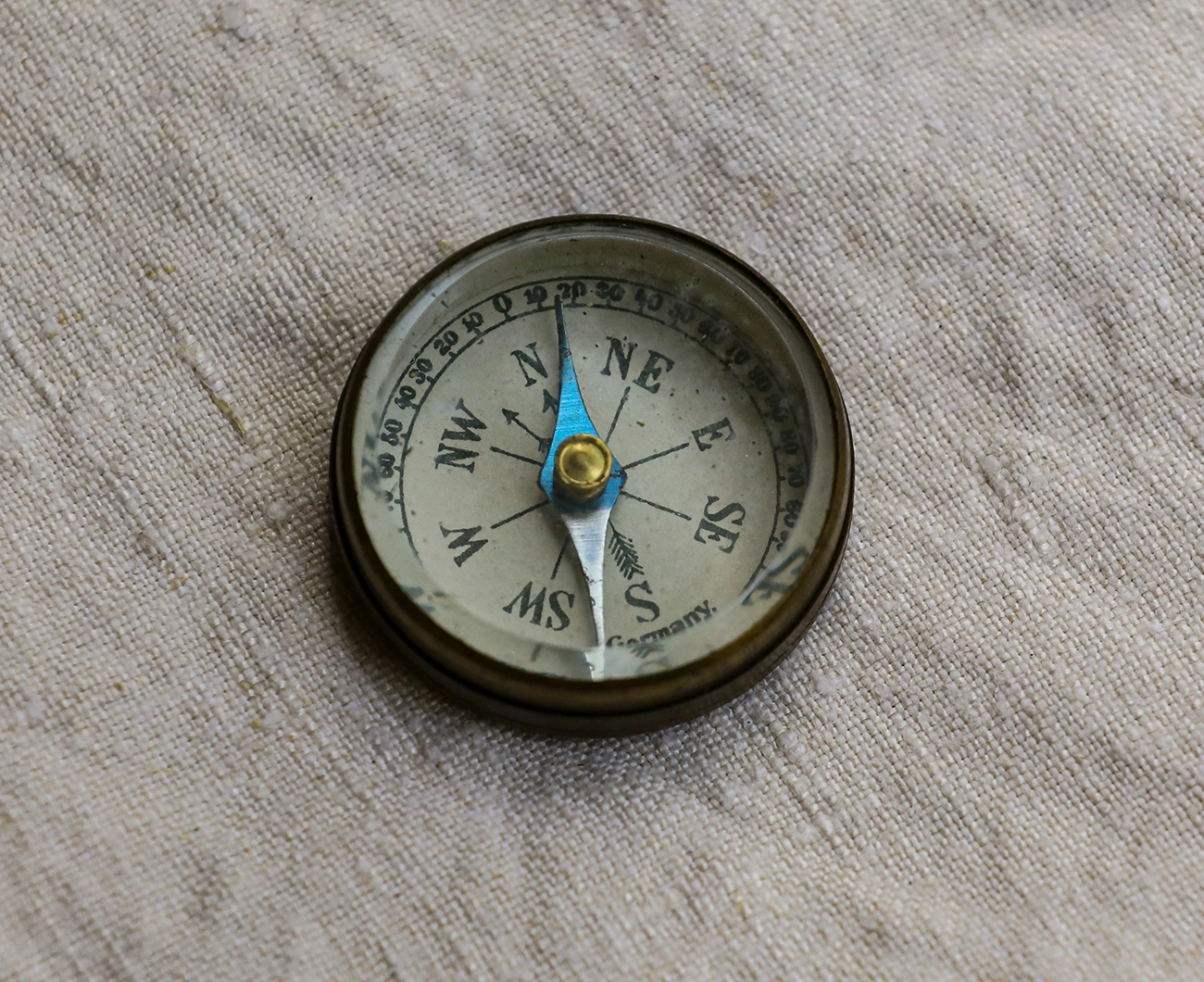 A vintage compass resting on woven fabric